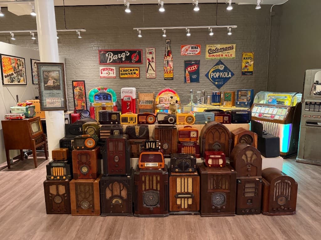 A colorful wall of vintage radios, jukeboxes, signs, and antique objects inside the Beautiful Things gallery.
